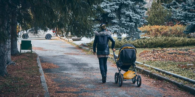 Persoon loopt met kinderwagen in het park